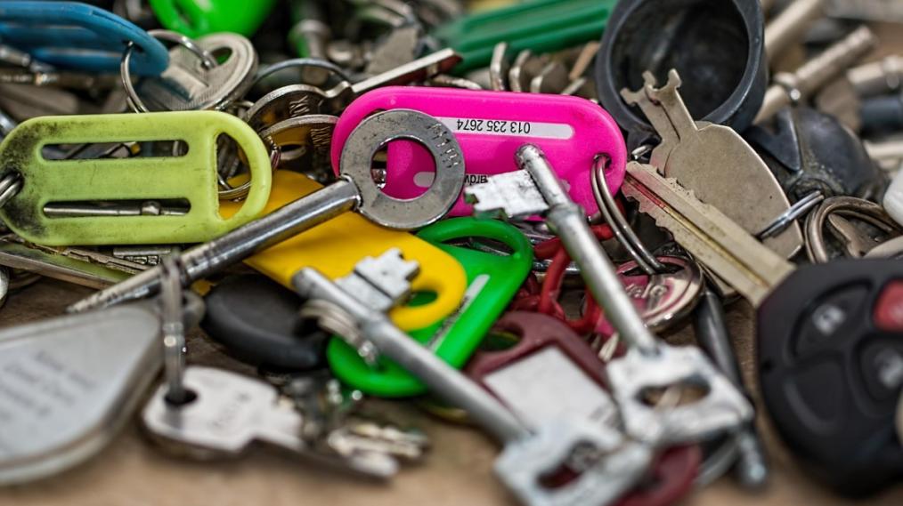 Close up photograph of a bundle of keys lying tangled on a wooden table.